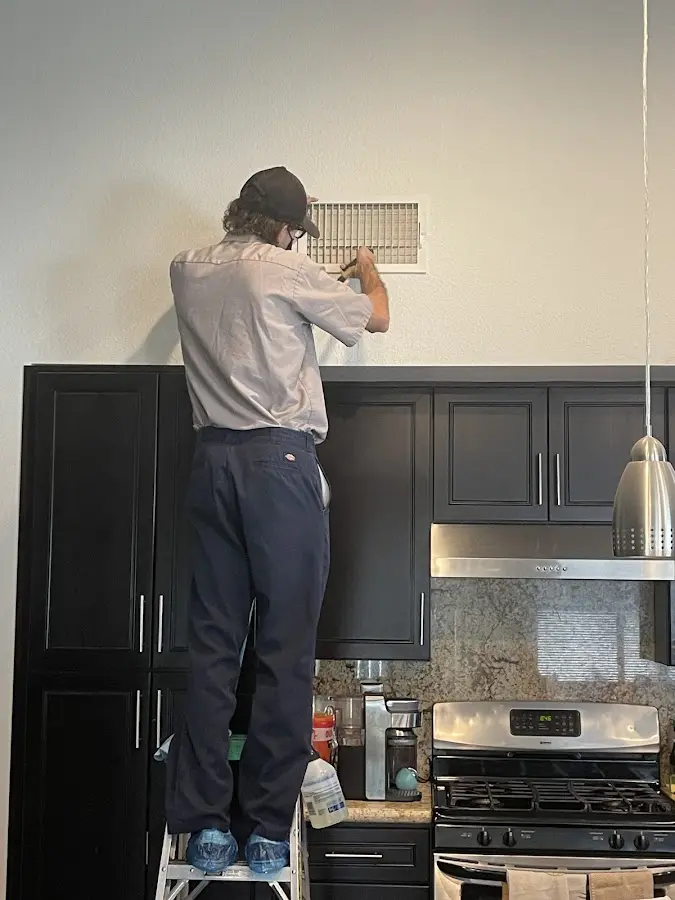 Technician inspecting an air vent during HVAC service in Robertsdale